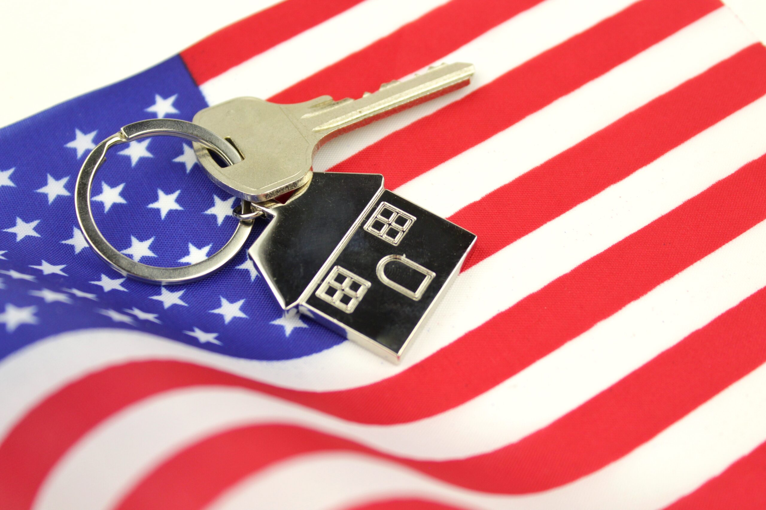 House keys on American flag representing mortgage loan options for first-time home buyers in the USA