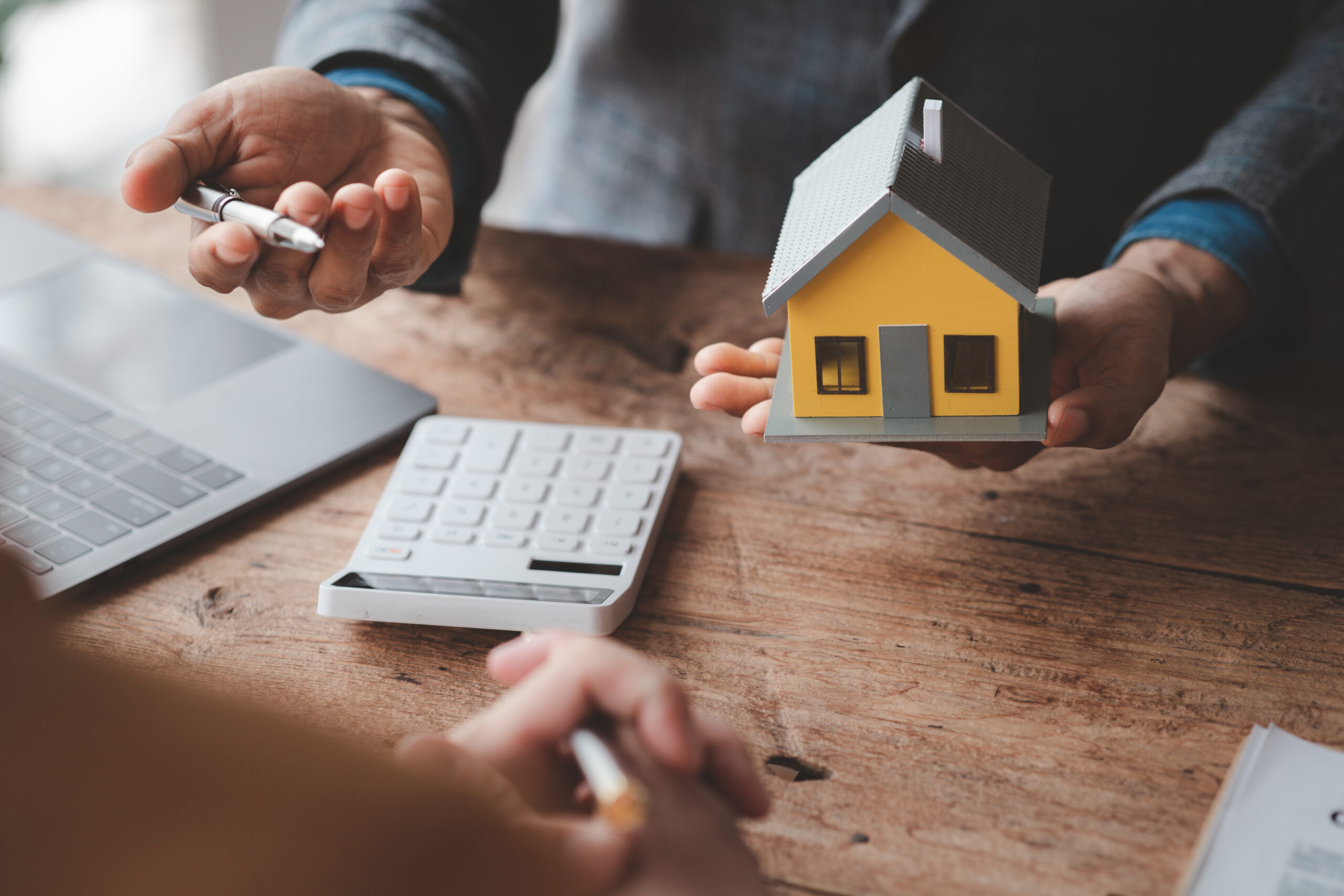 Hands holding house model and keys during home loan consultation